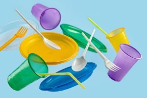 Flying,Multi-colored,Disposable,Plastic,Tableware,On,A,Blue,Background.,The